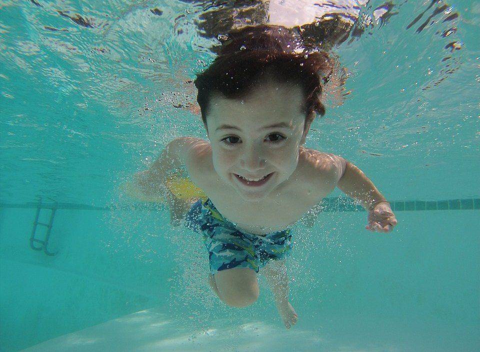 Мальчик в бассейне Занятия плаванием полезны